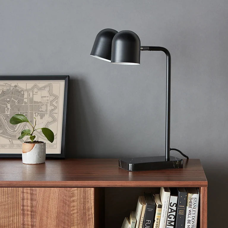 Twin-head adjustable table lamp, in black on a wooden cabinet