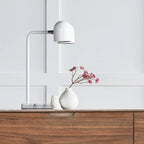 Twin-head adjustable table lamp, in matte white on a wooden sideboard