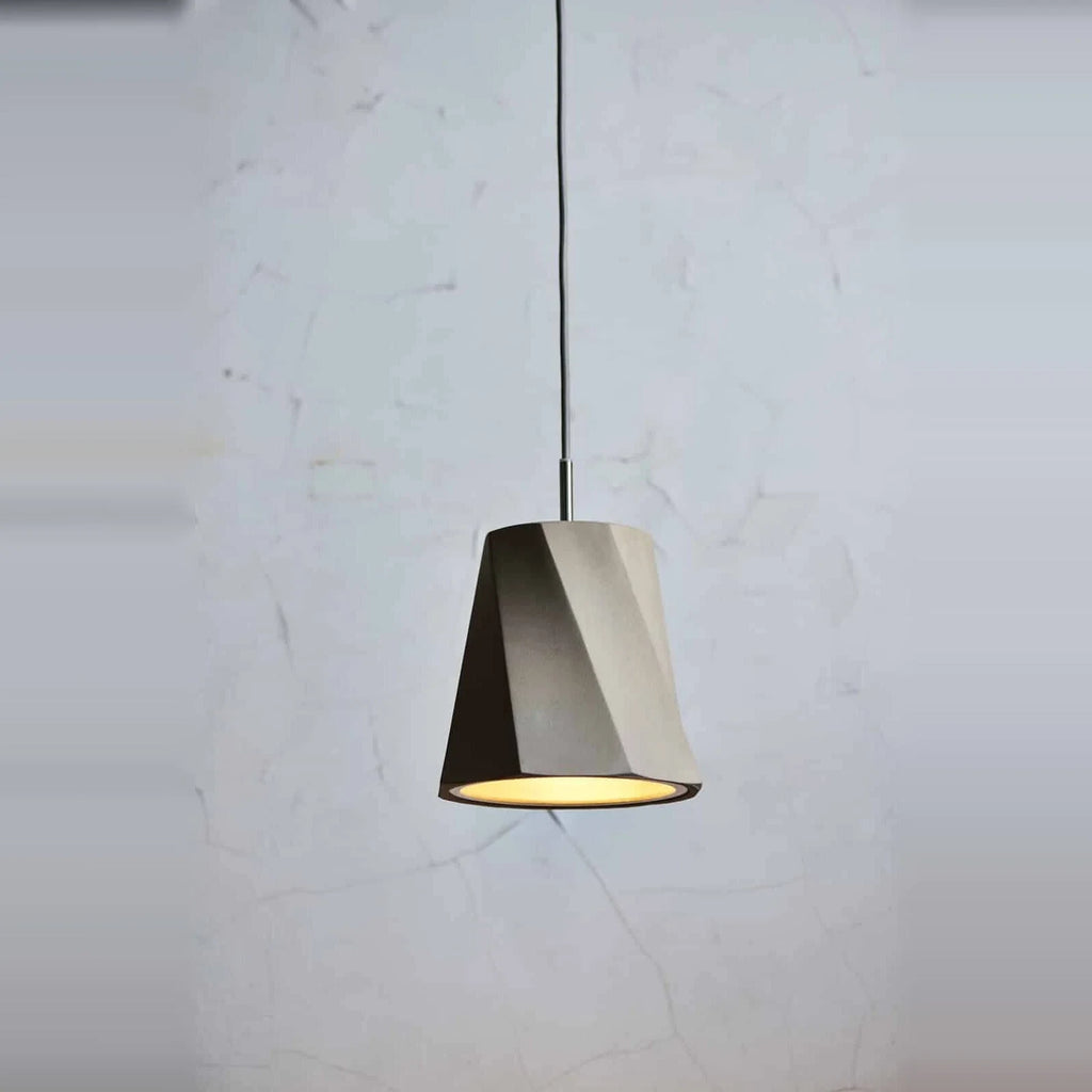 Twisted concrete pendant, against a concrete wall