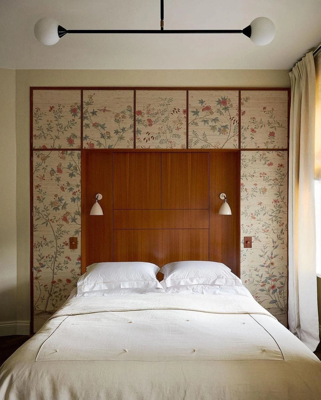 Two-globe pendant with horizontal arm, in black, above a bed
