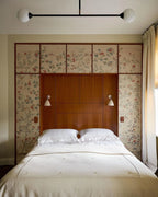 Two-globe pendant with horizontal arm, in black, above a bed
