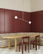 Two-globe pendant with horizontal arm, in white, above a dining table