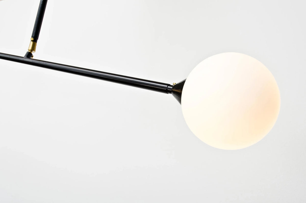 Two-globe pendant with horizontal arm, close-up of an opal glass globe