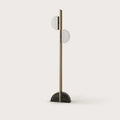Aged gold column floor lamp with two scalloped opal shades, on a half-round black marble base, against a plain wall