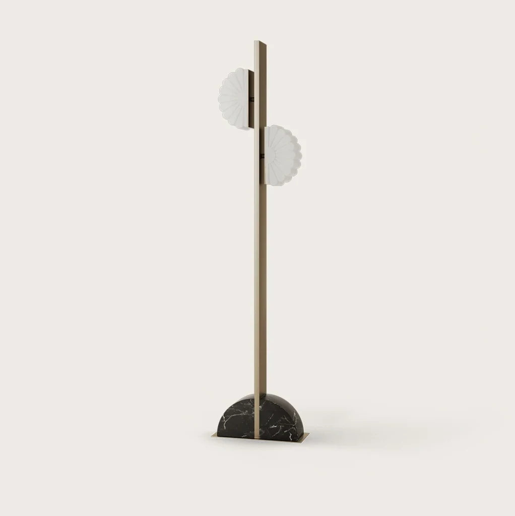 Aged gold column floor lamp with two scalloped opal shades, on a half-round black marble base, against a plain wall