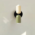 Two-tone up and down wall light, in beige and green near a plant