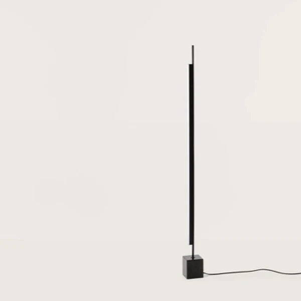 Vertical LED bar floor lamp with black marble cube base, on a black marble cube, against a plain wall, second view