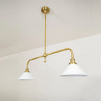 Two-light gold bar pendant with white cone shades, in a room