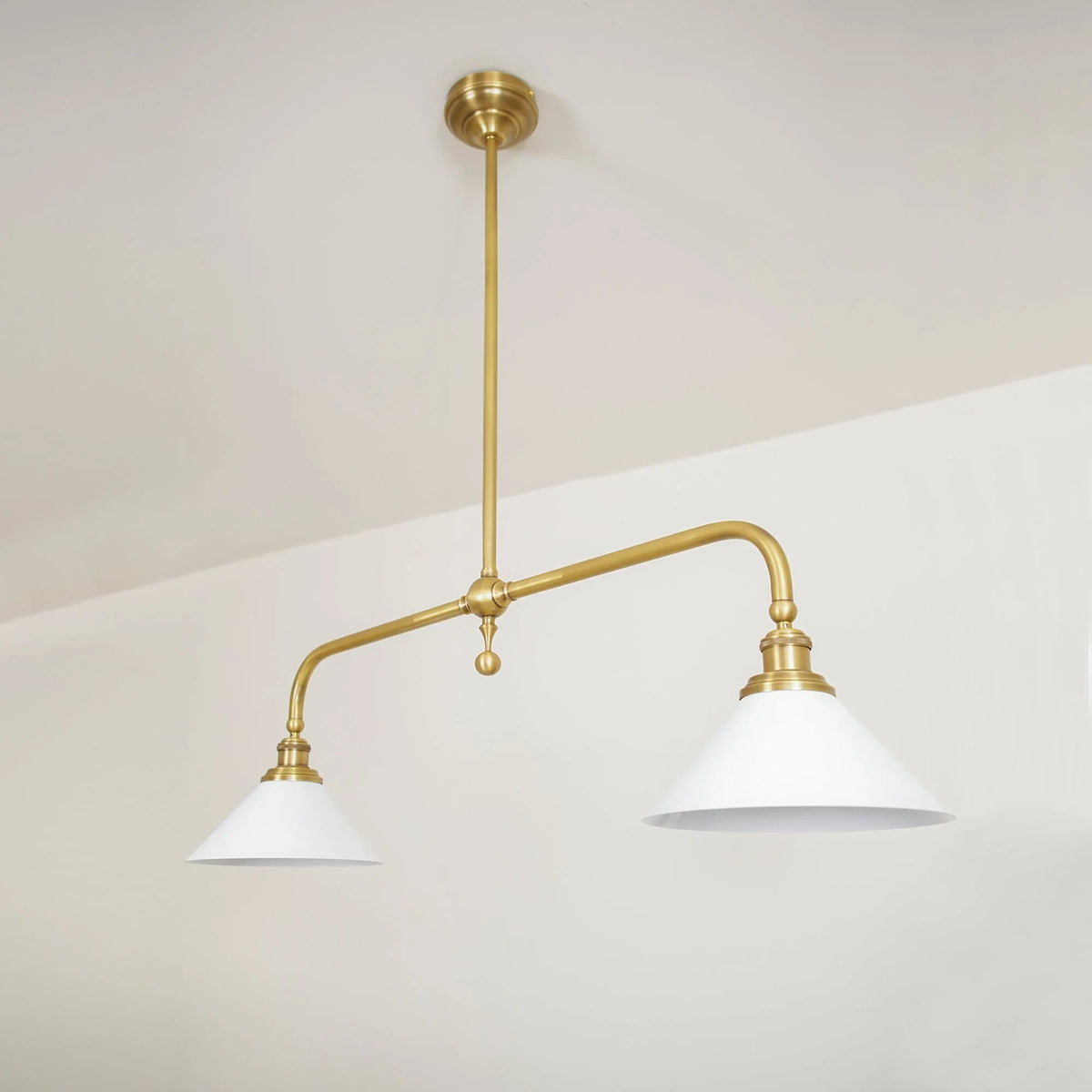 Two-light gold bar pendant with white cone shades, in a room