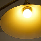Two-light gold bar pendant with white cone shades, lit from below