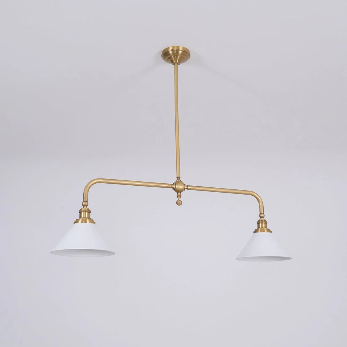 Two-light gold bar pendant with white cone shades, in a room