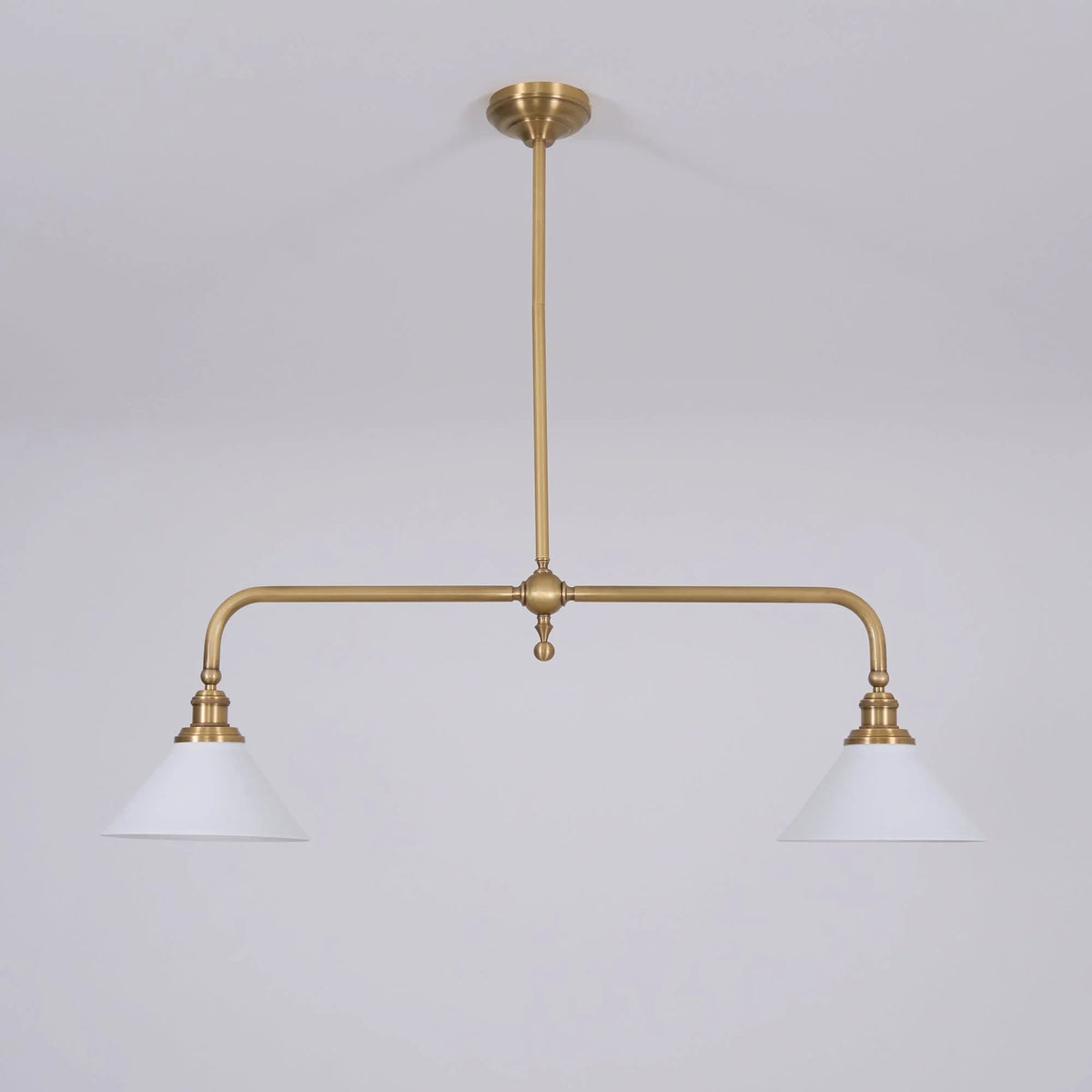 Two-light gold bar pendant with white cone shades, in a room