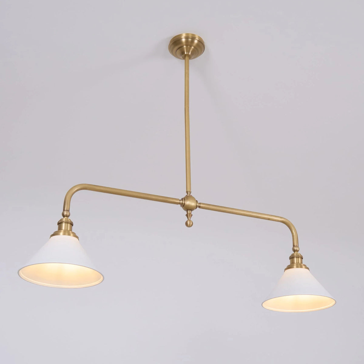 Two-light gold bar pendant with white cone shades, in a room