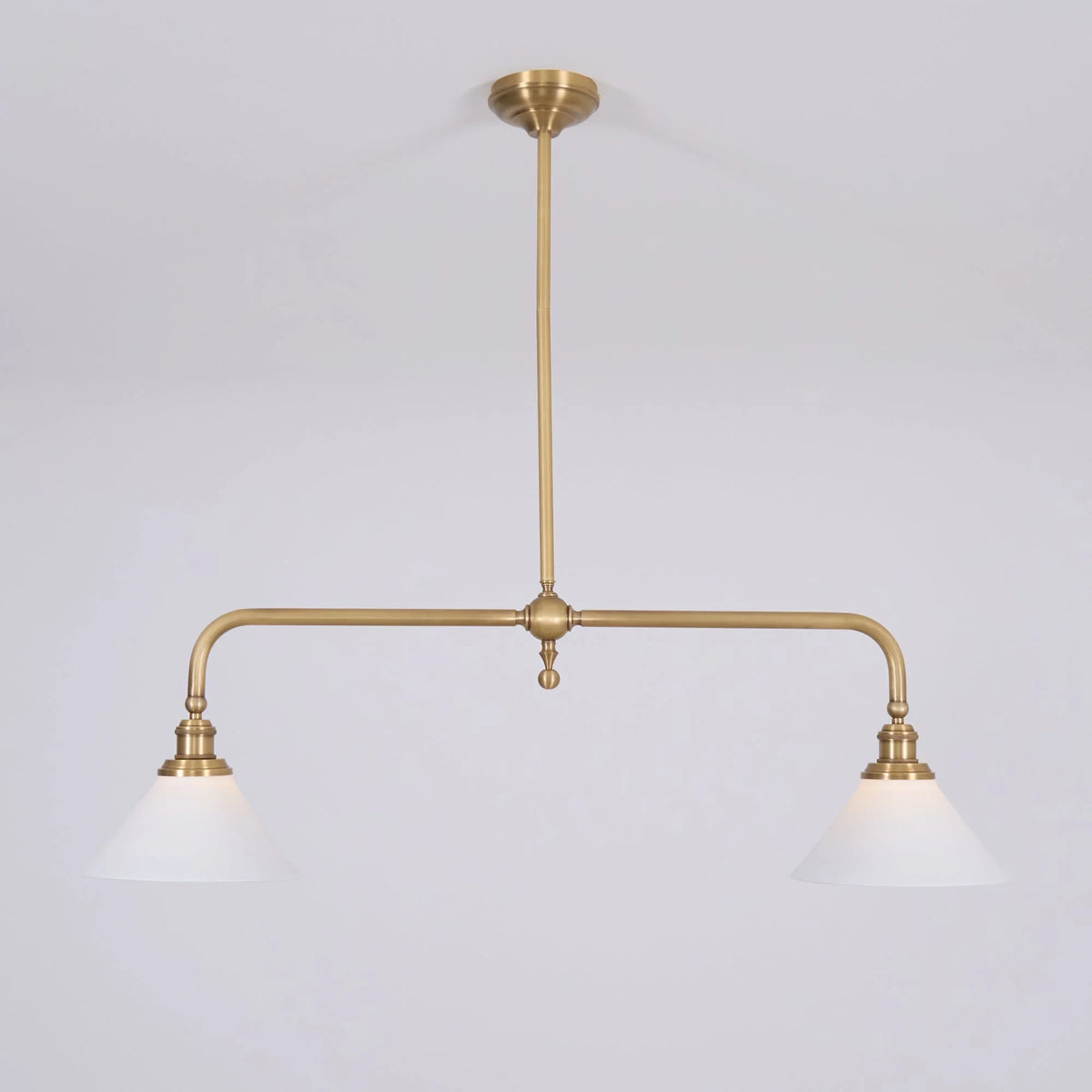 Two-light gold bar pendant with white cone shades, in a room