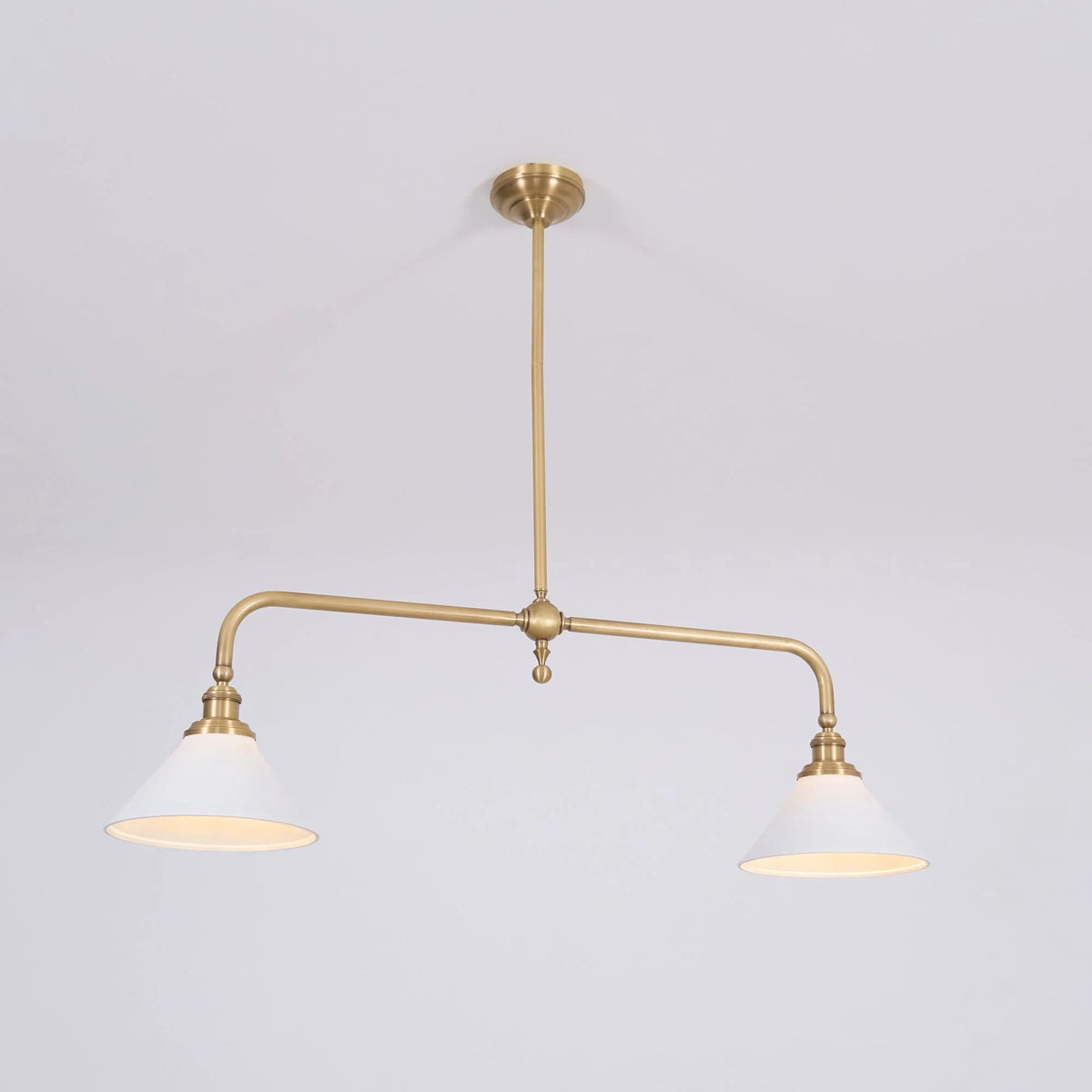 Two-light gold bar pendant with white cone shades, in a room
