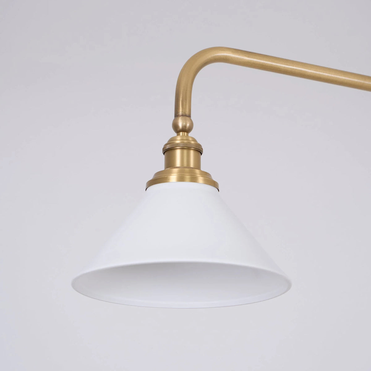 Two-light gold bar pendant with white cone shades, close-up of a shade