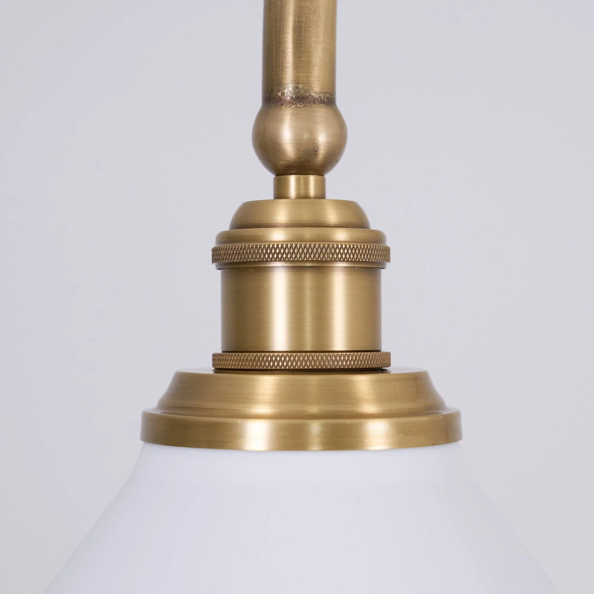 Two-light gold bar pendant with white cone shades, close-up of the fitting