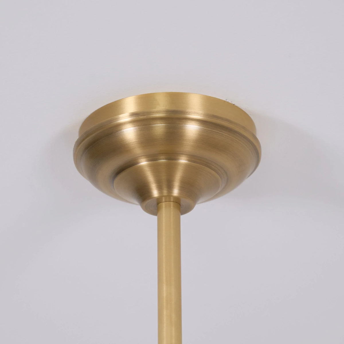 Two-light gold bar pendant with white cone shades, close-up of the ceiling plate