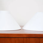 Two-light gold bar pendant with white cone shades, spare shades on a sideboard
