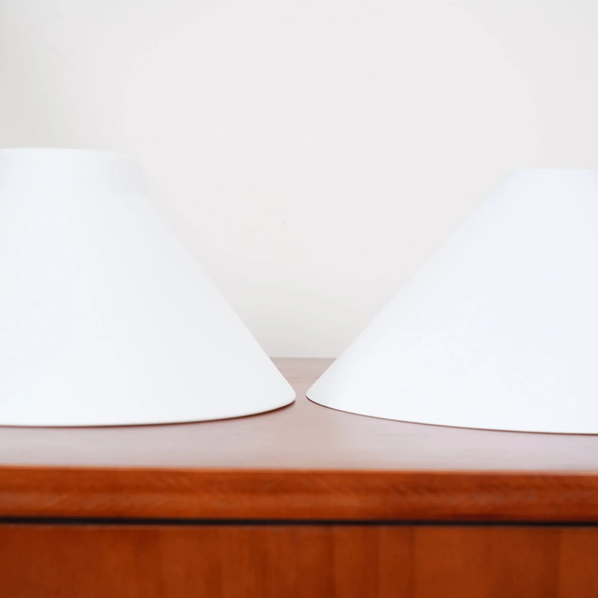 Two-light gold bar pendant with white cone shades, spare shades on a sideboard