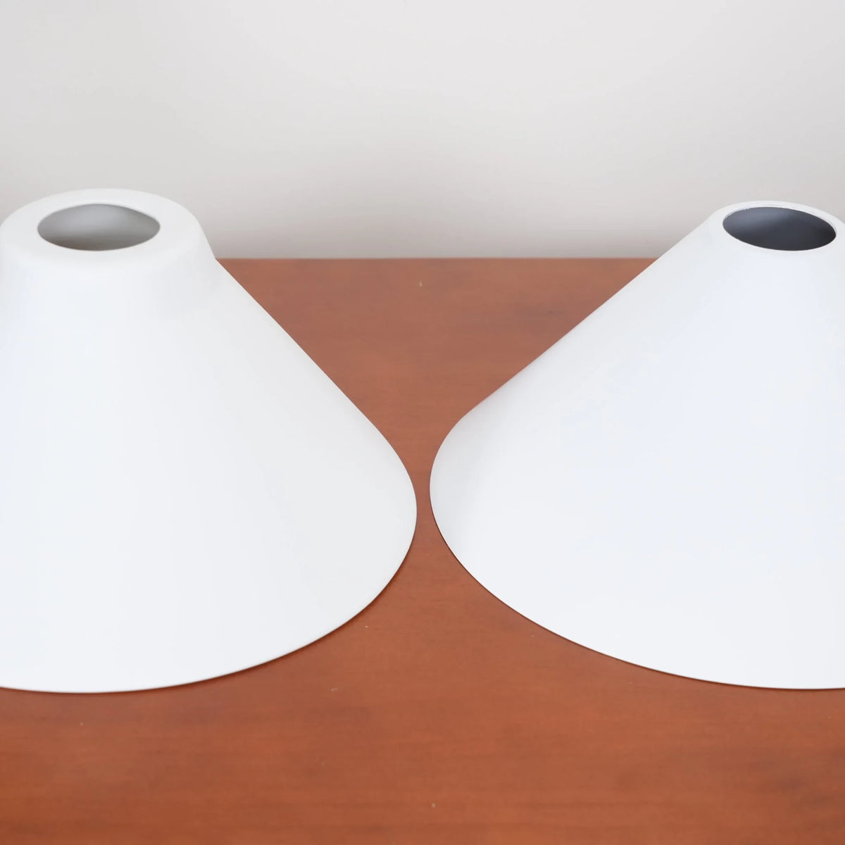 Two-light gold bar pendant with white cone shades, spare shades on a sideboard