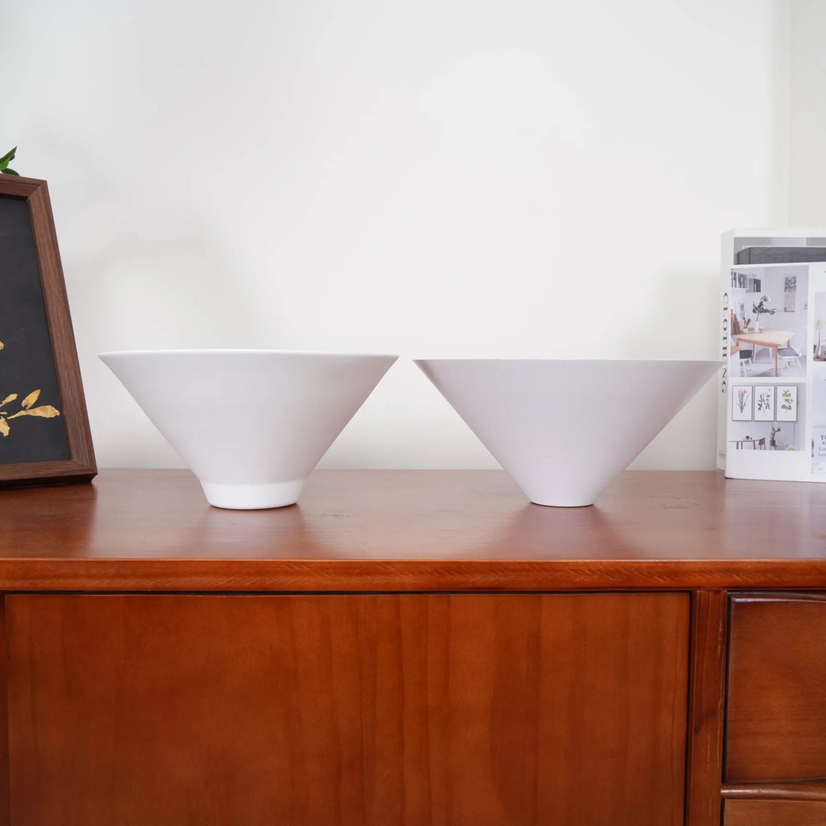 Two-light gold bar pendant with white cone shades, spare shades on a sideboard
