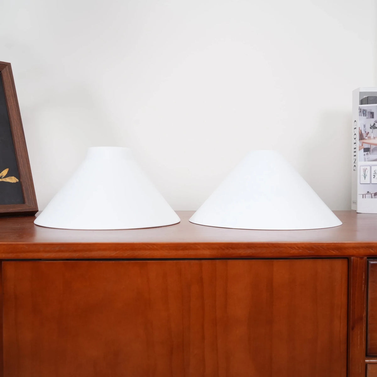Two-light gold bar pendant with white cone shades, spare shades on a sideboard