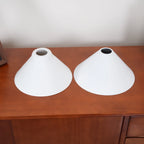 Two-light gold bar pendant with white cone shades, spare shades on a sideboard
