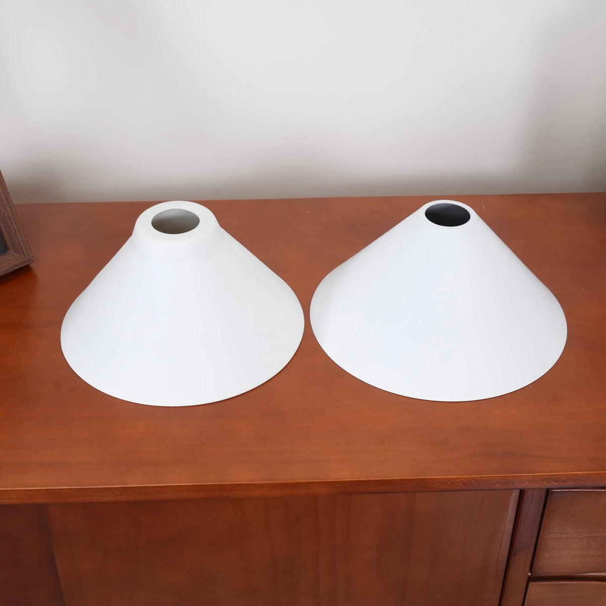 Two-light gold bar pendant with white cone shades, spare shades on a sideboard