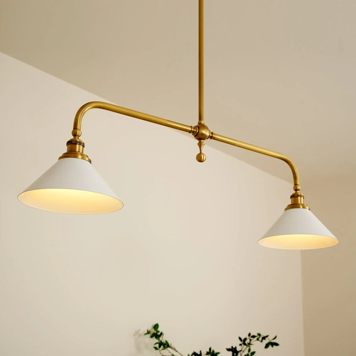 Two-light gold bar pendant with white cone shades, in a room