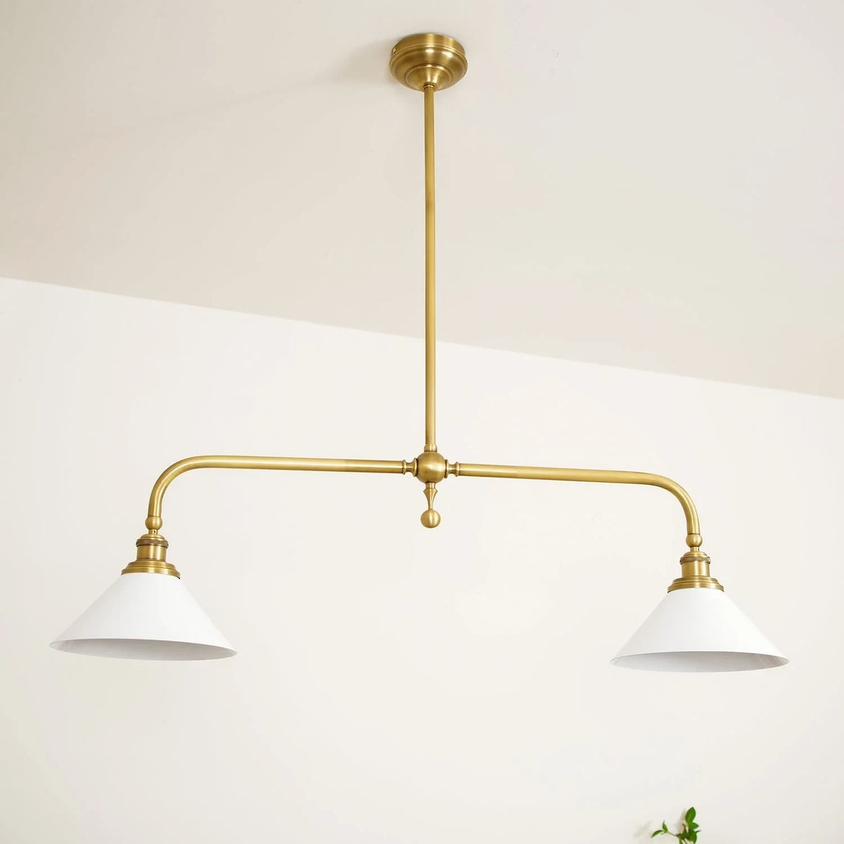 Two-light gold bar pendant with white cone shades, in a room