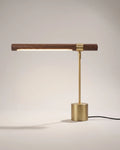 Walnut and brushed gold linear desk lamp, lit on a white background