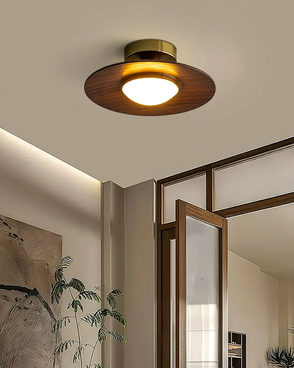 Low profile walnut and gold flush ceiling light, lit near a glass door