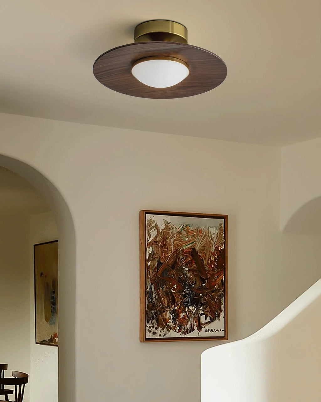 Low profile walnut and gold flush ceiling light, lit in an arched hallway