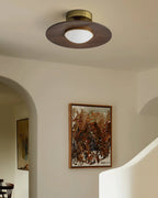 Low profile walnut and gold flush ceiling light, lit in an arched hallway