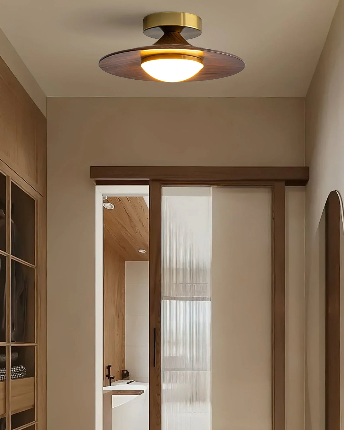 Low profile walnut and gold flush ceiling light, lit in a narrow corridor