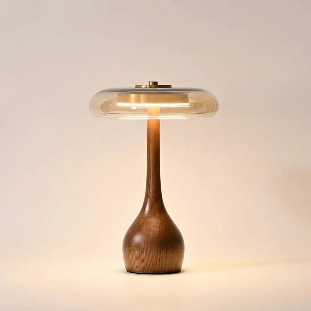 Walnut-tone timber table lamp with a tinted glass disc, Statuesque, lit