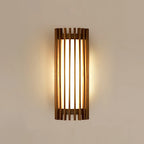 Walnut wood slatted wall light, lit on a plain wall