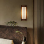 Walnut wood slatted wall light, beside a bed