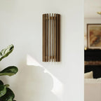 Walnut wood slatted wall light, on a wall by a plant