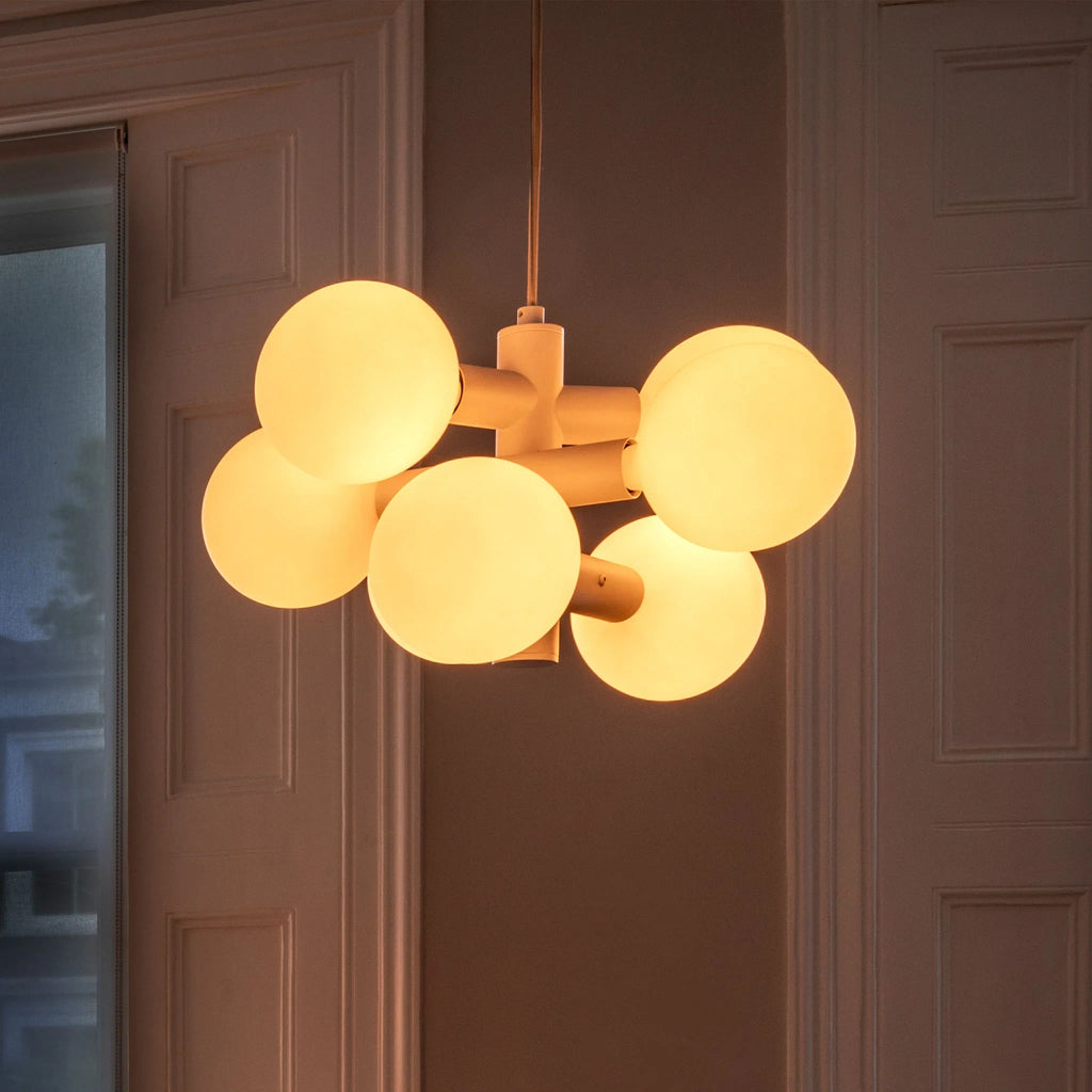 White steel globe cluster chandelier, lit warm in a hallway