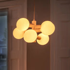 White steel globe cluster chandelier, lit warm in a hallway