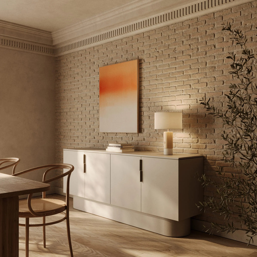 Wood and marble table lamp with drum shade, on a cream sideboard