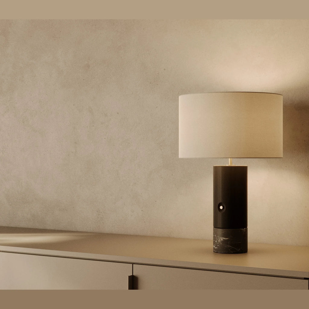 Wood and marble table lamp with drum shade, in black wood and black marble, on a shelf