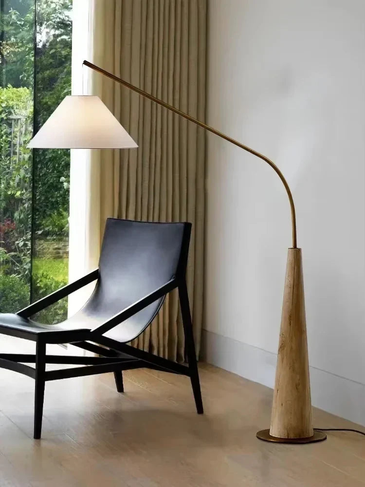 Wooden arc floor lamp, beside a lounge chair by a window