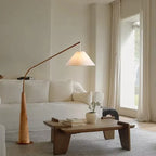 Wooden arc floor lamp, beside a cream sofa